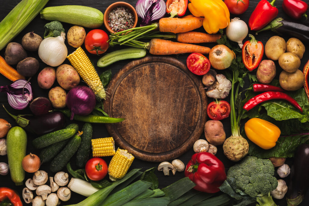 Fresh organic vegetables and wooden board with copy space background. Healthy natural food. Tomato, lettuce, carrot, pepper, potato and other cooking ingredients top view